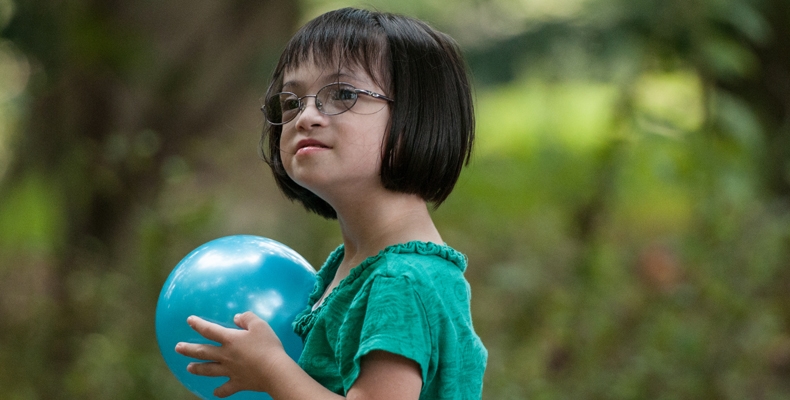 Young girl holding a blue playground ball.