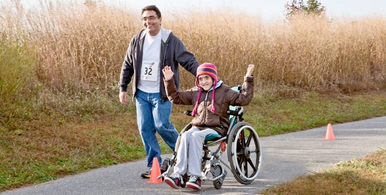 Man assist a boy to cross the finish line as he rasies his arms in celebration.