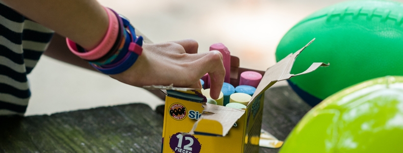 Sidewalk chalk and playground balls on a picnic table.